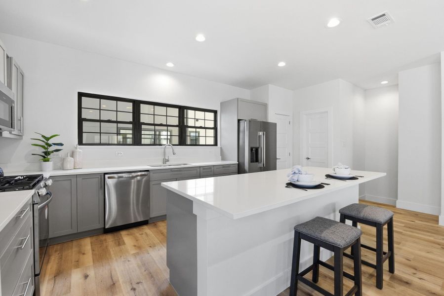 (Photos are from the Model Home - and for representation only)  Oversized quartz countertop with bar seating, perfect for entertaining and casual gatherings.