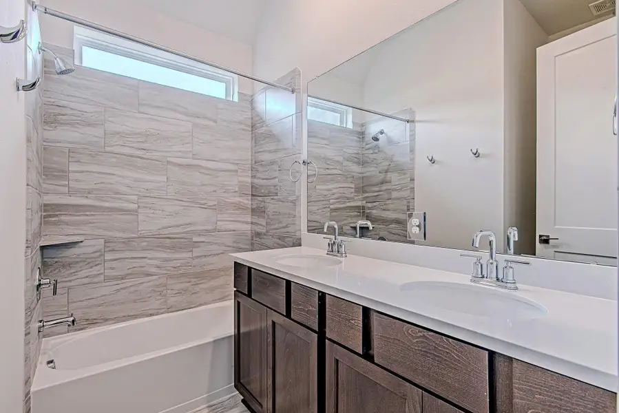 This well-appointed guest bath features a double vanity and a tub/shower combo with elevated tile detail—because even your guests deserve the VIP treatment. This well-appointed guest bath features a double vanity and a tub/shower combo with elevated tile detail—because even your guests deserve the VIP treatment.