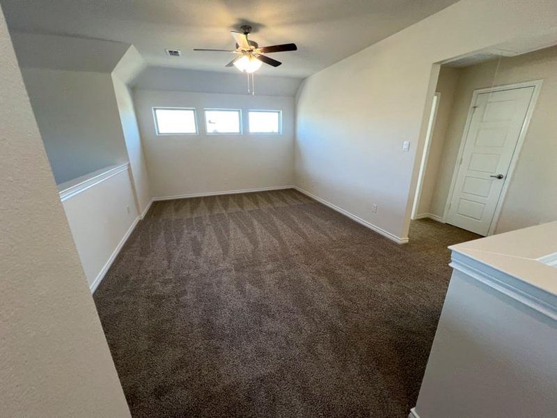 Spare room featuring dark carpet, attic access, and ceiling fan