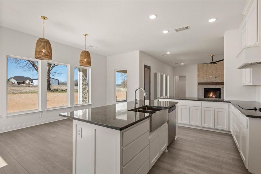 Kitchen featuring a large fireplace, visible vents, dark stone counters, a sink, and stainless steel dishwasher