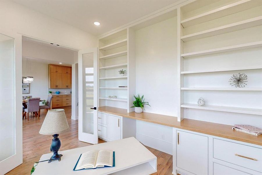 Office area with built in shelves and light hardwood / wood-style floors