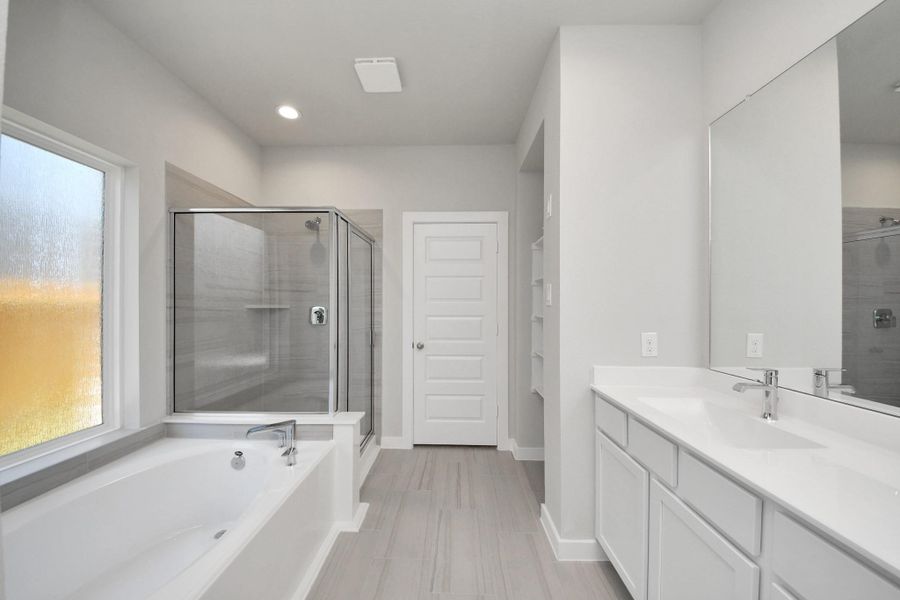 Delight in a spacious walk-in shower enveloped in stylish tile surround, unwind in a separate garden tub adorned with custom detailing, and elevate your daily routine at the elegant vanity, now equipped with double sinks, light countertops, modern hardware, and beautiful recessed lights. Sample photo of completed home with similar floor plan. Actual colors and selections may vary. Delight in a spacious walk-in shower enveloped in stylish tile surround, unwind in a separate garden tub adorned with custom detailing, and elevate your daily routine at the elegant vanity, now equipped with double sinks, light countertops, modern hardware, and beautiful recessed lights. Sample photo of completed home with similar floor plan. Actual colors and selections may vary.