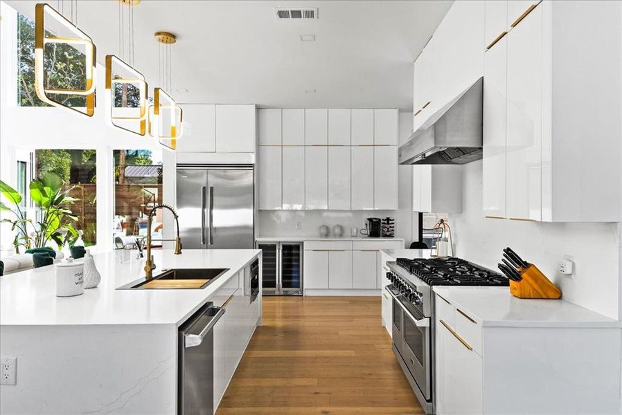 Kitchen with pendant lighting, white cabinetry, premium appliances, and wrap-around prep area