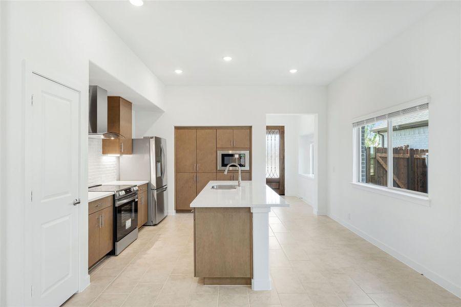 Open kitchen with wood cabinets, center island, white countertops, and stainless steel appliances on tile floors