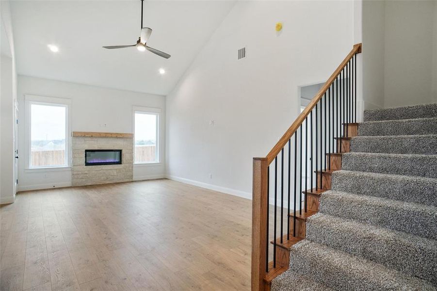 Unfurnished living room with high vaulted ceiling, light hardwood / wood-style floors, and ceiling fan