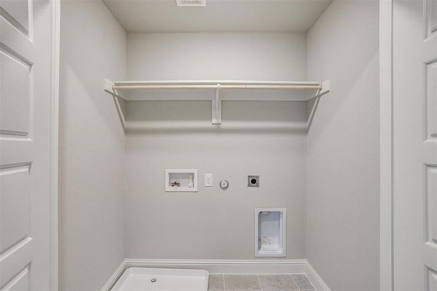 Laundry room with hookup for a gas dryer, hookup for an electric dryer, hookup for a washing machine, and light tile patterned floors