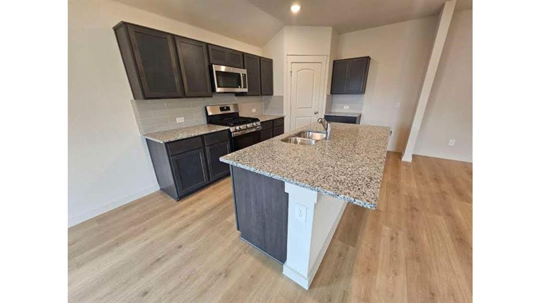 Contemporary kitchen featuring dark wood cabinetry, stainless steel appliances, granite countertops, and a double basin sink Contemporary kitchen featuring dark wood cabinetry, stainless steel appliances, granite countertops, and a double basin sink
