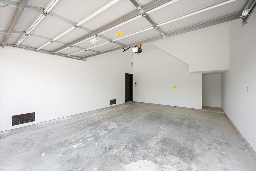 This spacious attached garage features a clean, freshly painted interior with a durable concrete floor, automatic overhead door, and ample room for parking, storage, or a future workspace, offering both functionality and convenience.