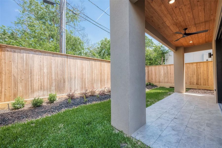 This is a covered patio area with a tiled floor and a wooden ceiling, featuring a ceiling fan. It opens up to a private, fenced backyard with some young landscaping along the fence line. The space is bright and airy, offering a nice outdoor living extension to the home. This is a covered patio area with a tiled floor and a wooden ceiling, featuring a ceiling fan. It opens up to a private, fenced backyard with some young landscaping along the fence line. The space is bright and airy, offering a nice outdoor living extension to the home.