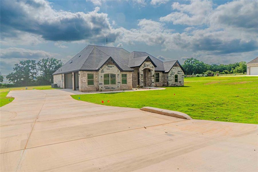 French country inspired facade featuring central AC and a front yard