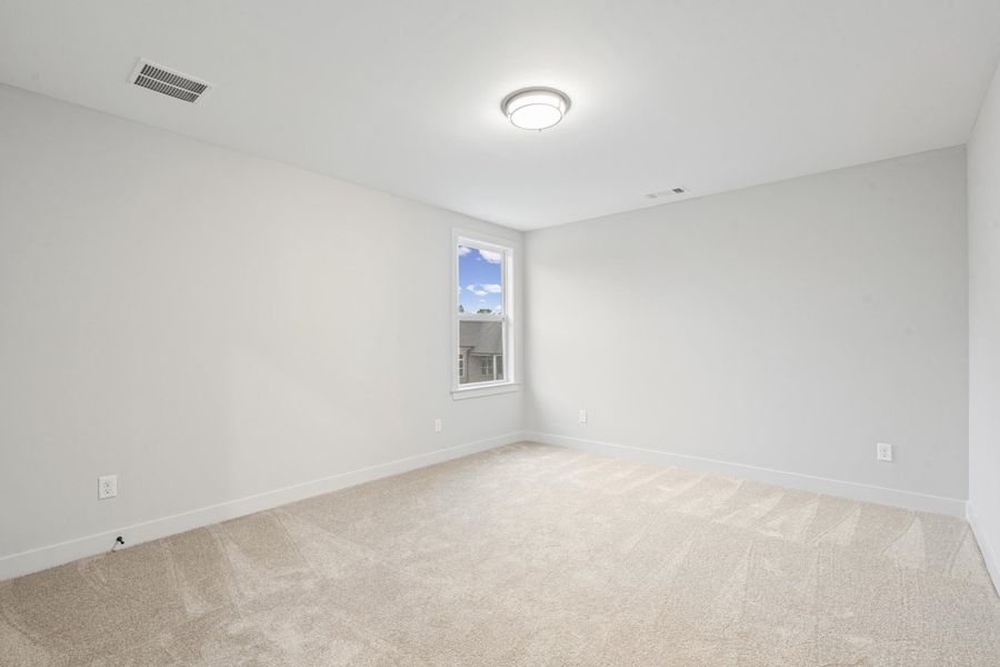 Spacious room with light-colored carpet flooring and white baseboards Spacious room with light-colored carpet flooring and white baseboards