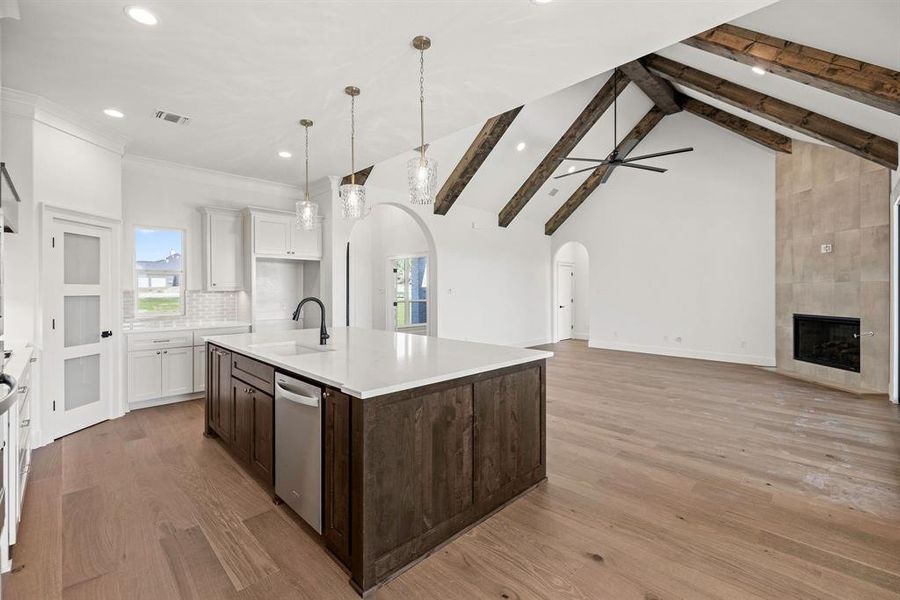 Kitchen featuring visible vents, stainless steel dishwasher, a sink, arched walkways, and dark brown cabinetry