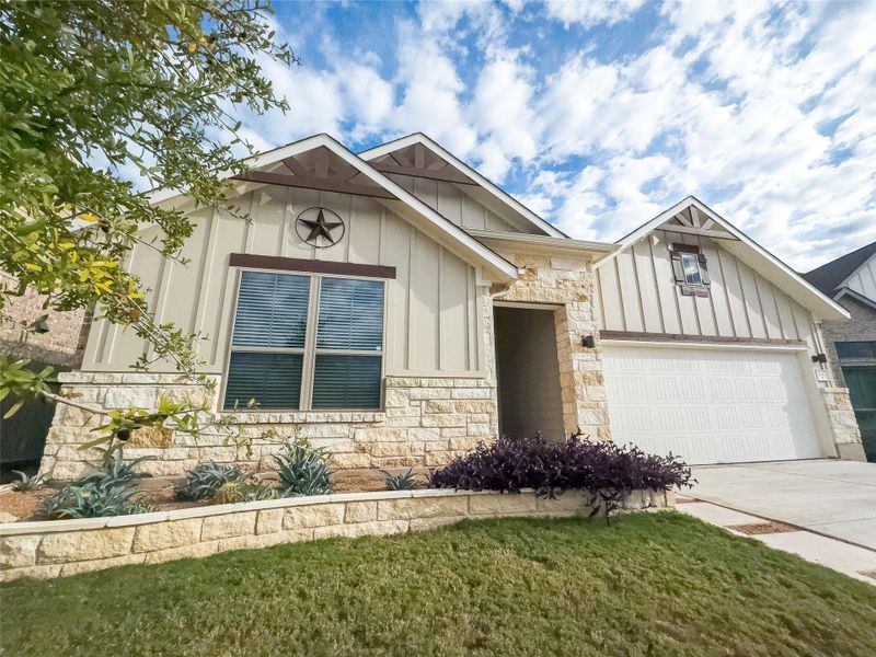 View of front facade with board and batten siding, driveway, stone siding, an attached garage, and a front yard View of front facade with board and batten siding, driveway, stone siding, an attached garage, and a front yard