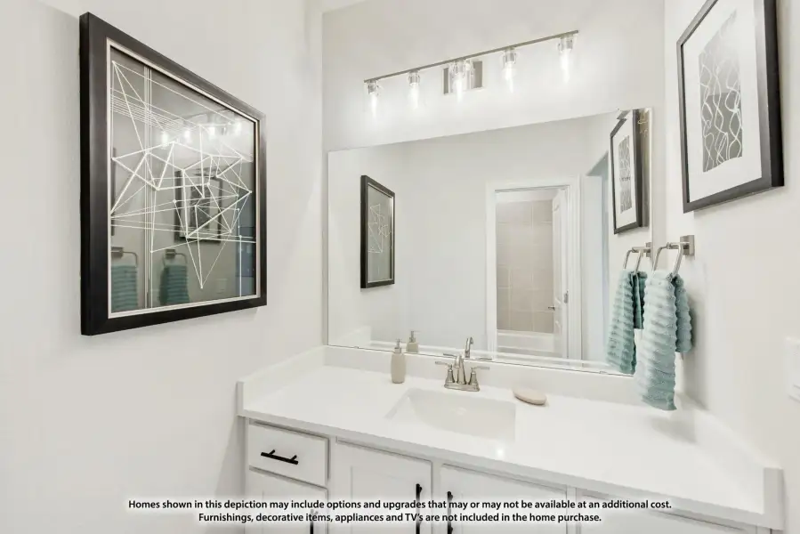 Bathroom vanity with white cabinets, quartz countertop, large mirror, and brushed nickel light fixture above sink
