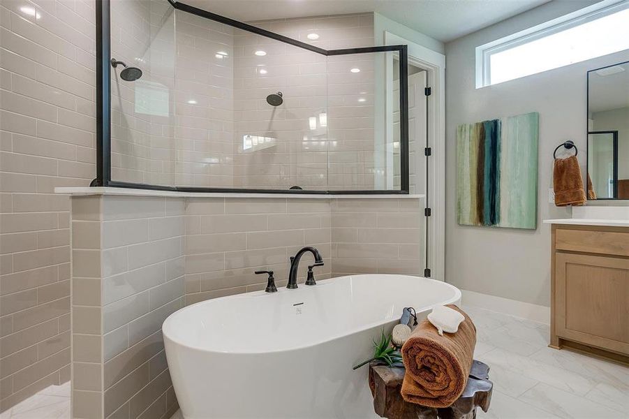 Full bathroom featuring marble finish floor, vanity, baseboards, a soaking tub, and tiled shower Full bathroom featuring marble finish floor, vanity, baseboards, a soaking tub, and tiled shower