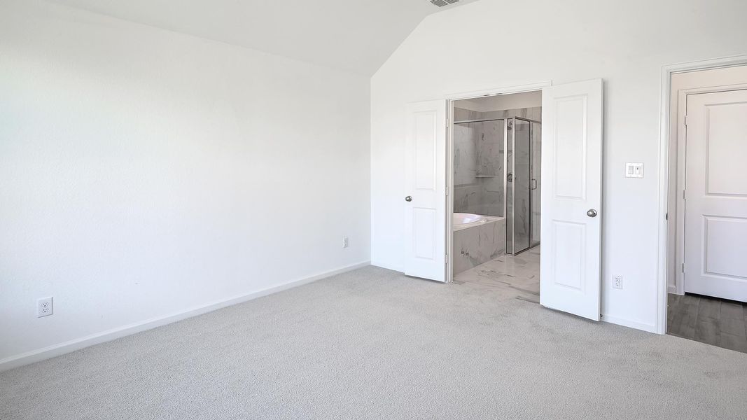 Unfurnished bedroom with light carpet, vaulted ceiling, and ensuite bathroom Unfurnished bedroom with light carpet, vaulted ceiling, and ensuite bathroom