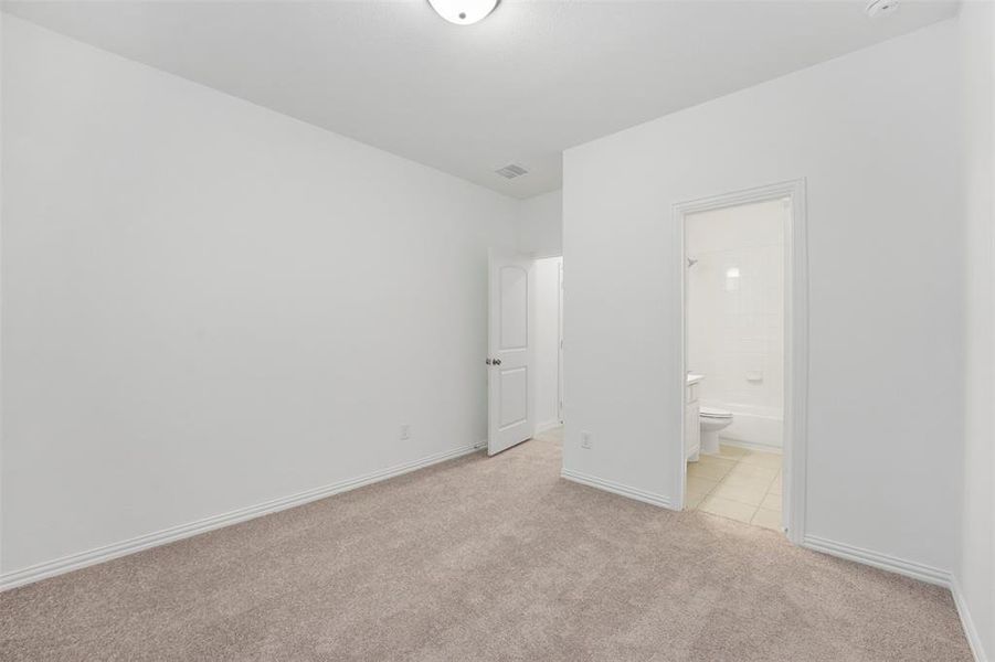 Unfurnished bedroom with ensuite bath and light colored carpet