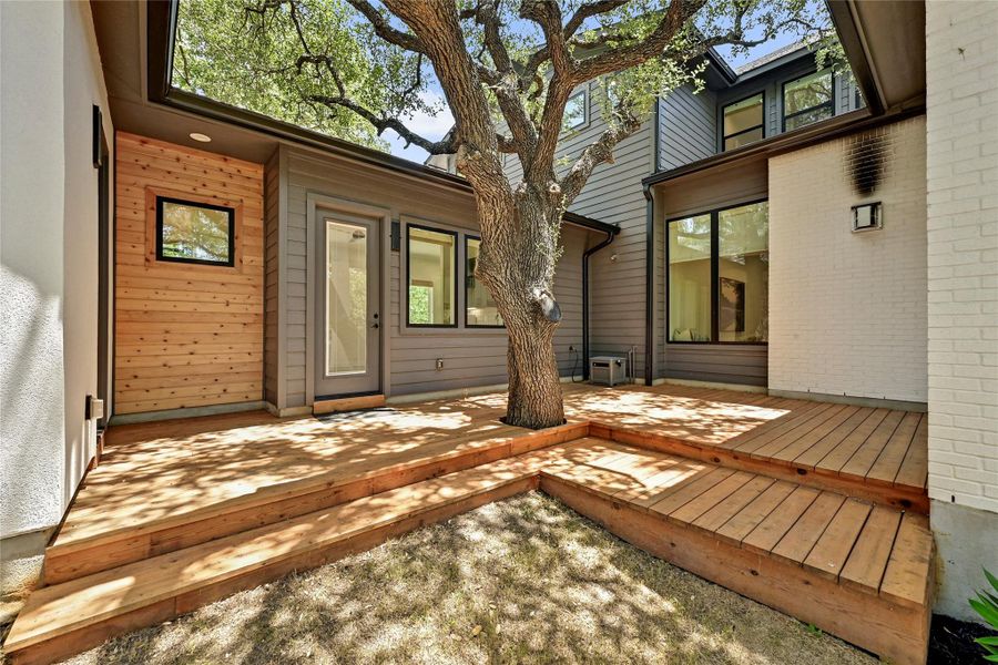 Wood deck connects the main house to the casita and wraps a preserved heritage oak, leading to a covered patio with ceiling fan — a private outdoor retreat framed by mature trees. Wood deck connects the main house to the casita and wraps a preserved heritage oak, leading to a covered patio with ceiling fan — a private outdoor retreat framed by mature trees.