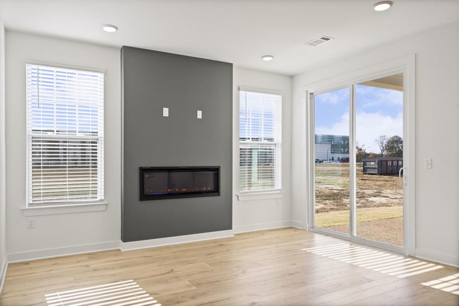 Unfurnished living room with a glass covered fireplace and light wood-style flooring