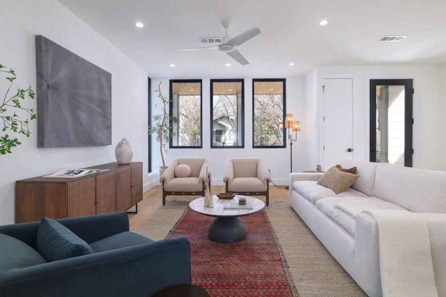 Living room with healthy amount of natural light, wood finished floors, a ceiling fan, and recessed lighting