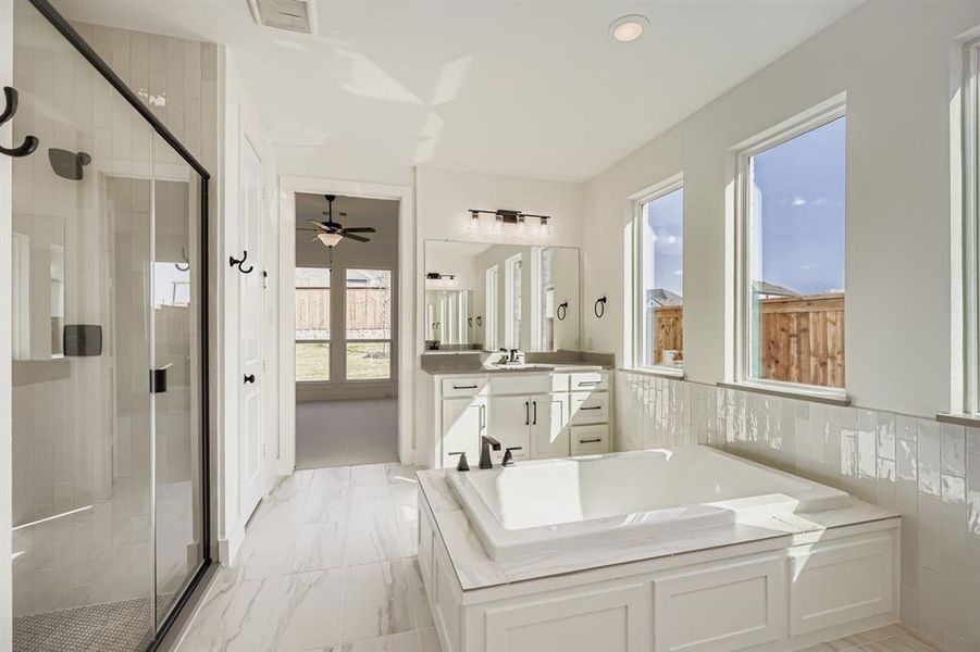Full bath with vanity, a garden tub, a shower stall, a ceiling fan, and light marble finish flooring Full bath with vanity, a garden tub, a shower stall, a ceiling fan, and light marble finish flooring