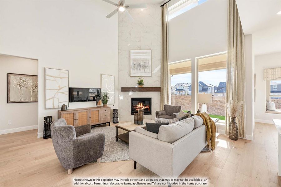 Living room with two-story ceiling, marble fireplace, hardwood floors, and large windows overlooking backyard Living room with two-story ceiling, marble fireplace, hardwood floors, and large windows overlooking backyard