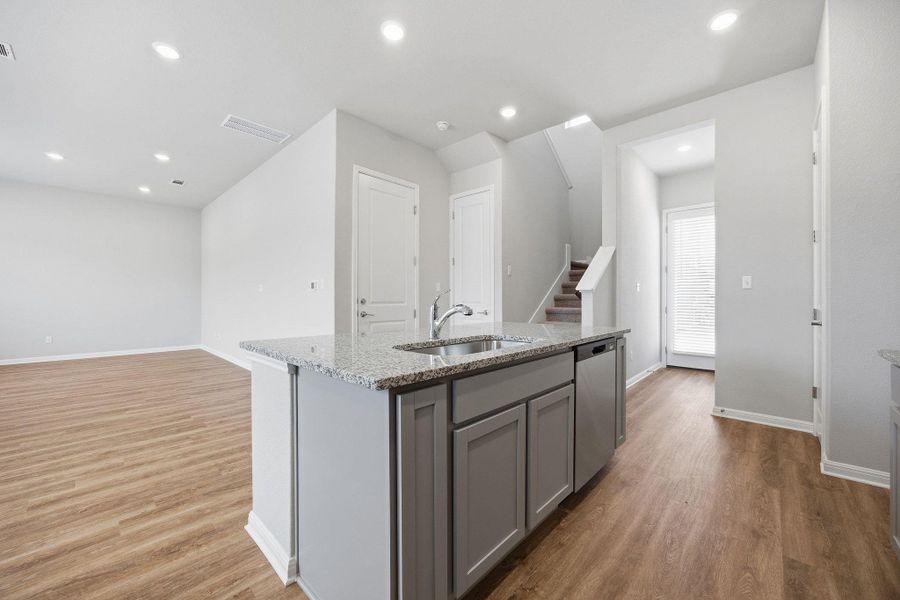 Kitchen featuring gray cabinets, a kitchen island with sink, light stone counters, light wood-style flooring, and recessed lighting