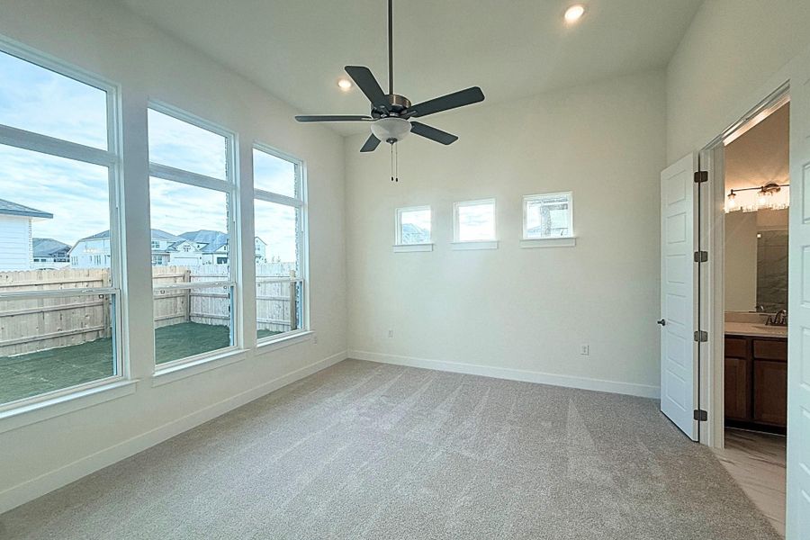 Spacious carpeted room featuring a ceiling fan with integrated lighting, recessed lighting, and multiple windows providing ample illumination