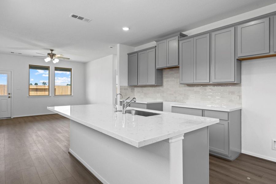 This light and bright kitchen features a large quartz island, custom stained cabinets, a large sink overlooking your family room, recessed lighting, and beautiful backsplash. This light and bright kitchen features a large quartz island, custom stained cabinets, a large sink overlooking your family room, recessed lighting, and beautiful backsplash.