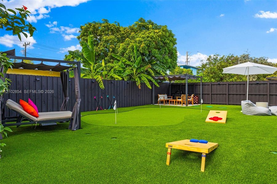 Private backyard featuring artificial turf, a built-in putting green, and a dark-stained wood privacy fence