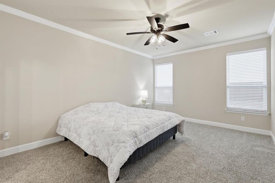 Bedroom featuring light colored carpet, crown molding, and ceiling fan