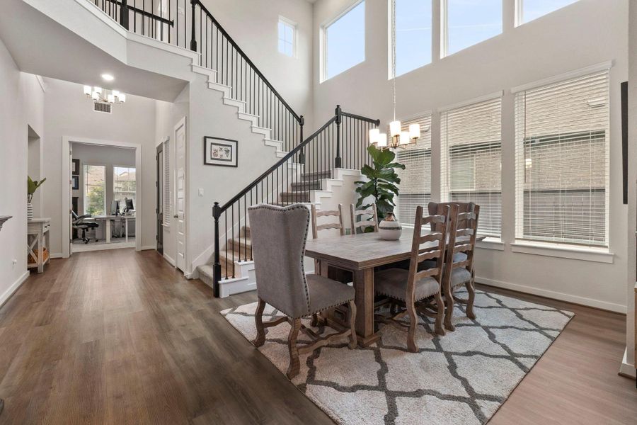 Two-story entryway featuring wood-finish flooring, a grand staircase with wrought iron balusters, and a contemporary chandelier