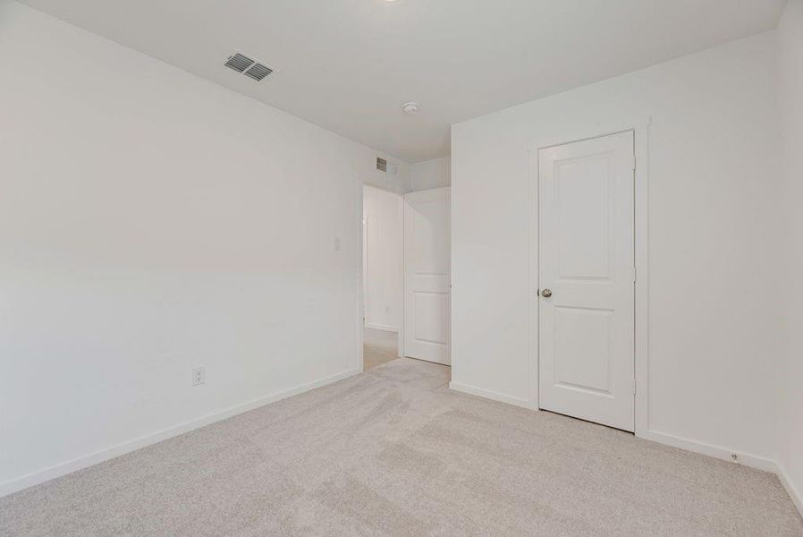 Unfurnished bedroom with light carpet and baseboards