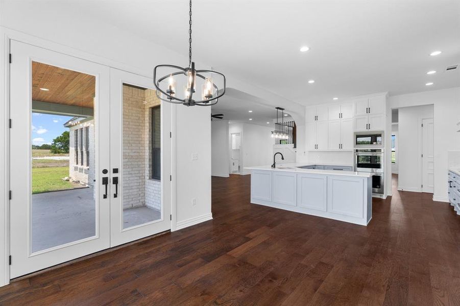 Kitchen featuring oven, a chandelier, black microwave, light countertops, and dark wood-style floors Kitchen featuring oven, a chandelier, black microwave, light countertops, and dark wood-style floors