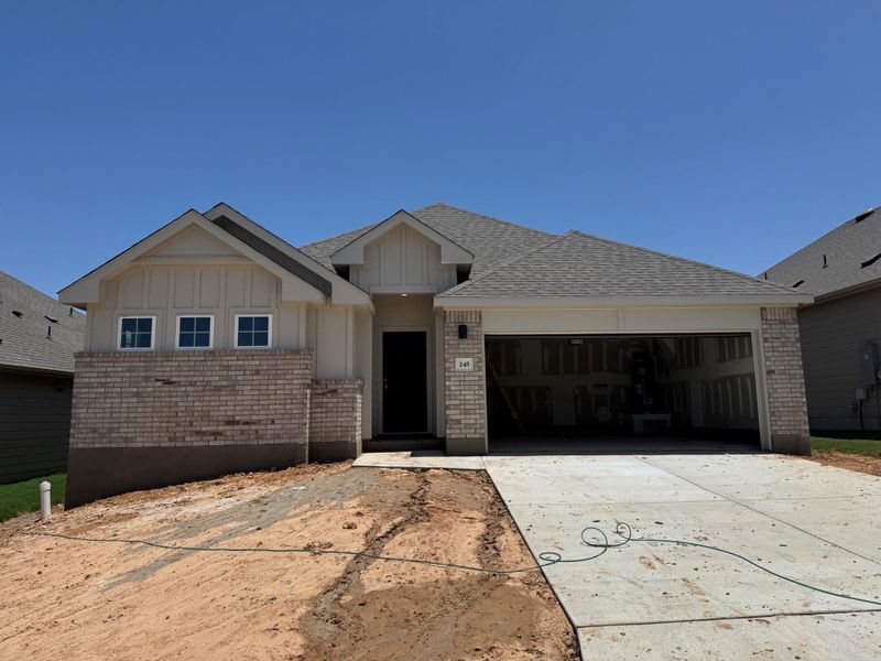 Single story home featuring brick siding, a garage, concrete driveway, and board and batten siding Single story home featuring brick siding, a garage, concrete driveway, and board and batten siding