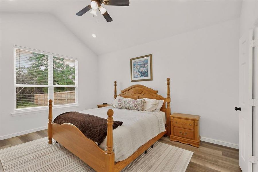 Vaulted ceiling bedroom featuring wood-finish flooring, recessed lighting, and a ceiling fan