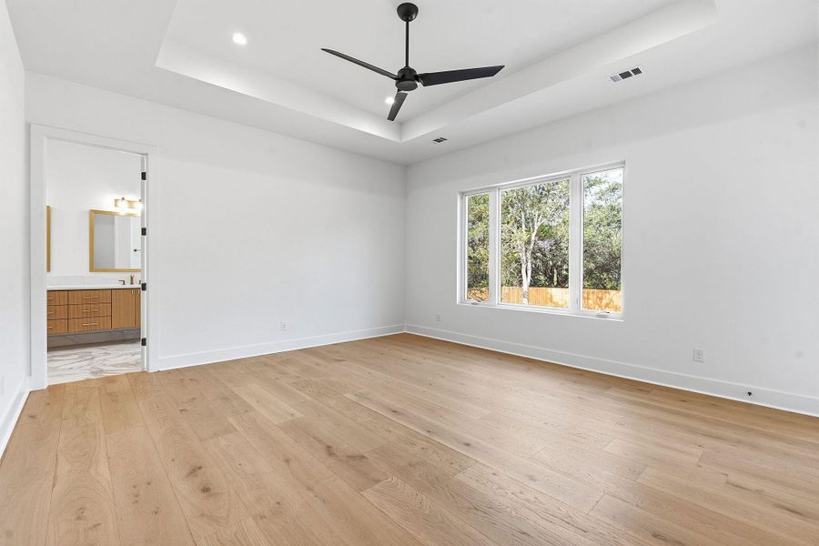 A tray ceiling highlights this bedroom complete with hardwood flooring and ensuite access.