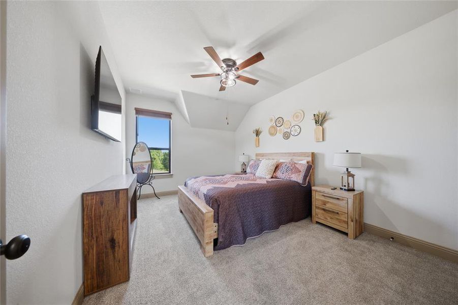 Spacious room featuring vaulted ceilings, a ceiling fan, a large window, and light carpeting