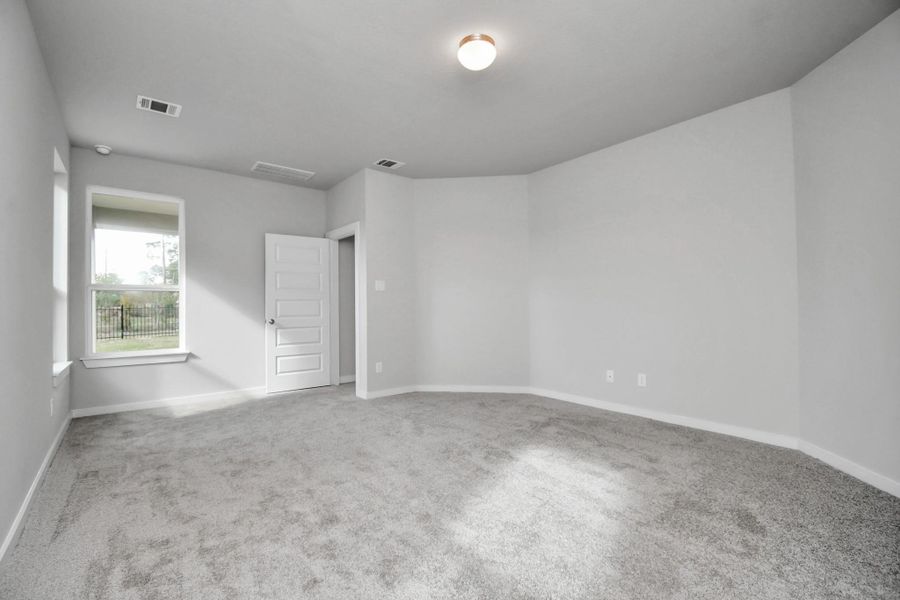 Escape and relax in the exquisite primary suite, a haven to unwind after a long day. The spacious room, boasts plush carpeting, soothing paint tones, high ceilings, and expansive windows adorned with privacy blinds. Sample photo of completed home with similar floor plan. Actual colors and selections may vary.
