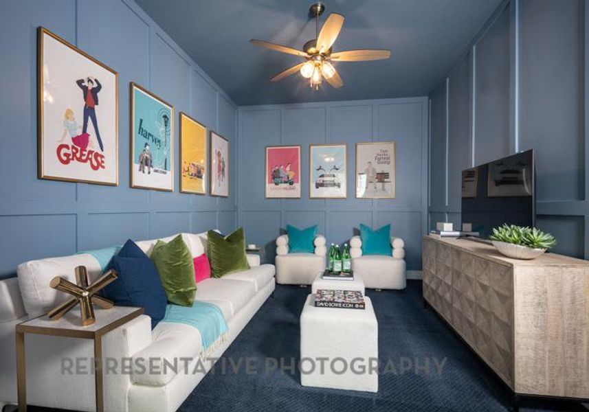 Living area with ceiling fan, dark colored carpet, and a decorative wall Living area with ceiling fan, dark colored carpet, and a decorative wall