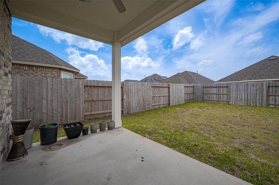Fenced backyard with green space.
