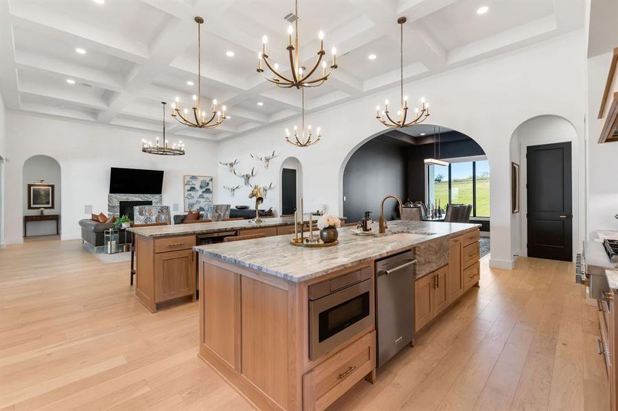 Kitchen featuring arched walkways, open floor plan, a towering ceiling, light stone counters, and light wood-style floors Kitchen featuring arched walkways, open floor plan, a towering ceiling, light stone counters, and light wood-style floors