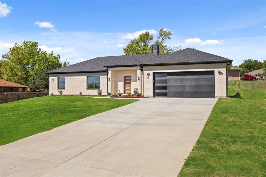 View of front of property featuring a garage and a front yard