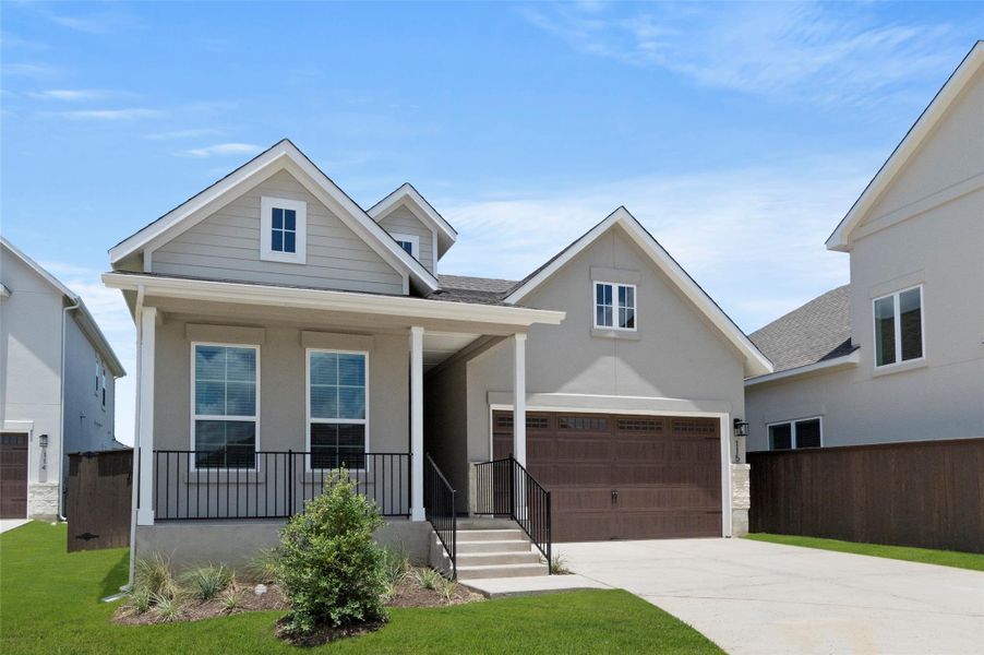 View of front of house with driveway, covered porch, a garage, and a shingled roof
