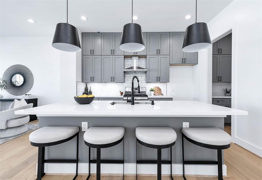 Large kitchen island with farmer sink, gas range, large cabinets and butlers pantry, half bath and pantry on the right.