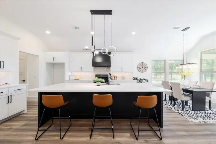 Kitchen featuring vaulted ceiling, backsplash, white cabinets, pendant lighting, and recessed lighting