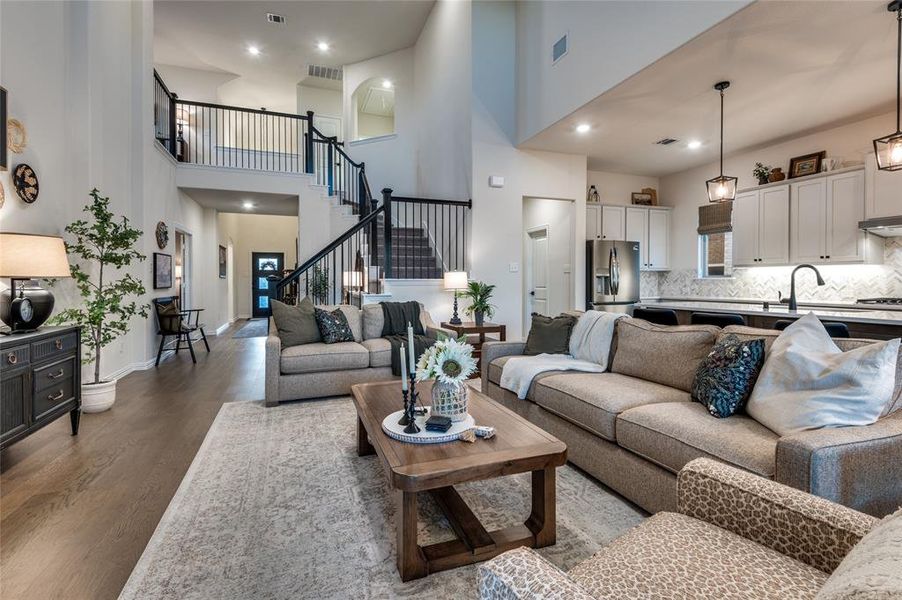 Living area with wood finished floors, stairway, recessed lighting, and a towering ceiling