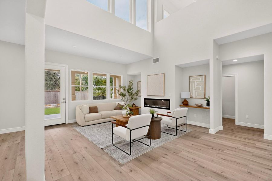 Double-height ceilings and a modern fireplace elevate this light-filled living area with wood floors.