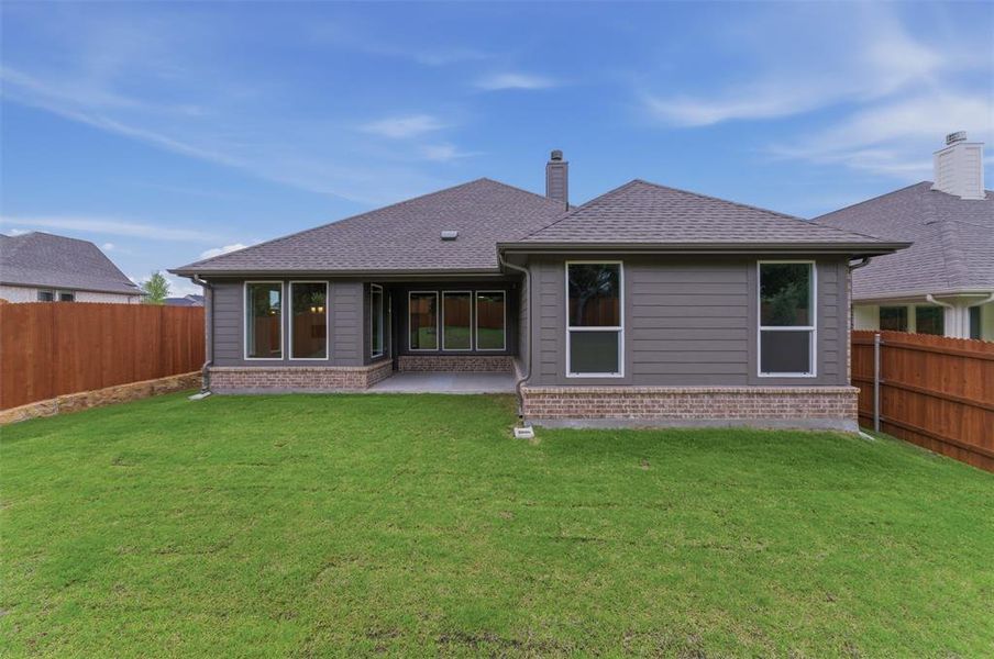 Expansive backyard featuring a manicured lawn, a concrete patio, a privacy fence, and a modern exterior with brick and horizontal siding