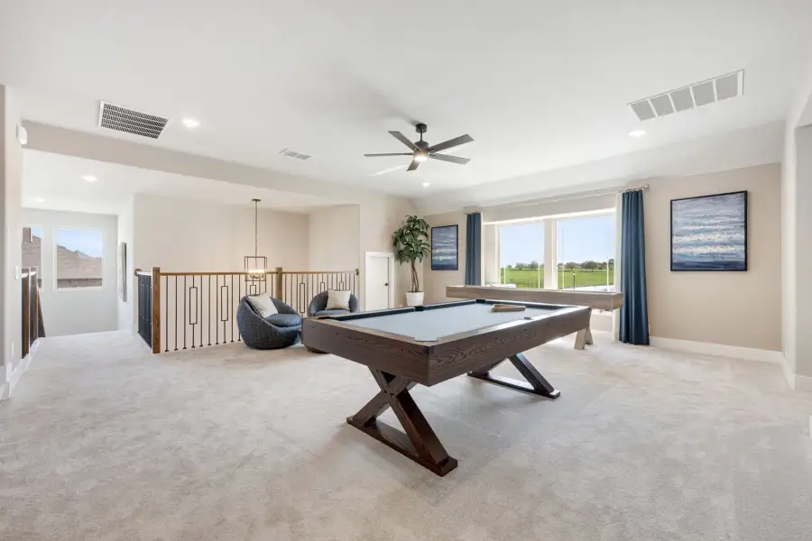 Upstairs bonus room with pool table, carpet flooring, ceiling fan, and open staircase railing Upstairs bonus room with pool table, carpet flooring, ceiling fan, and open staircase railing